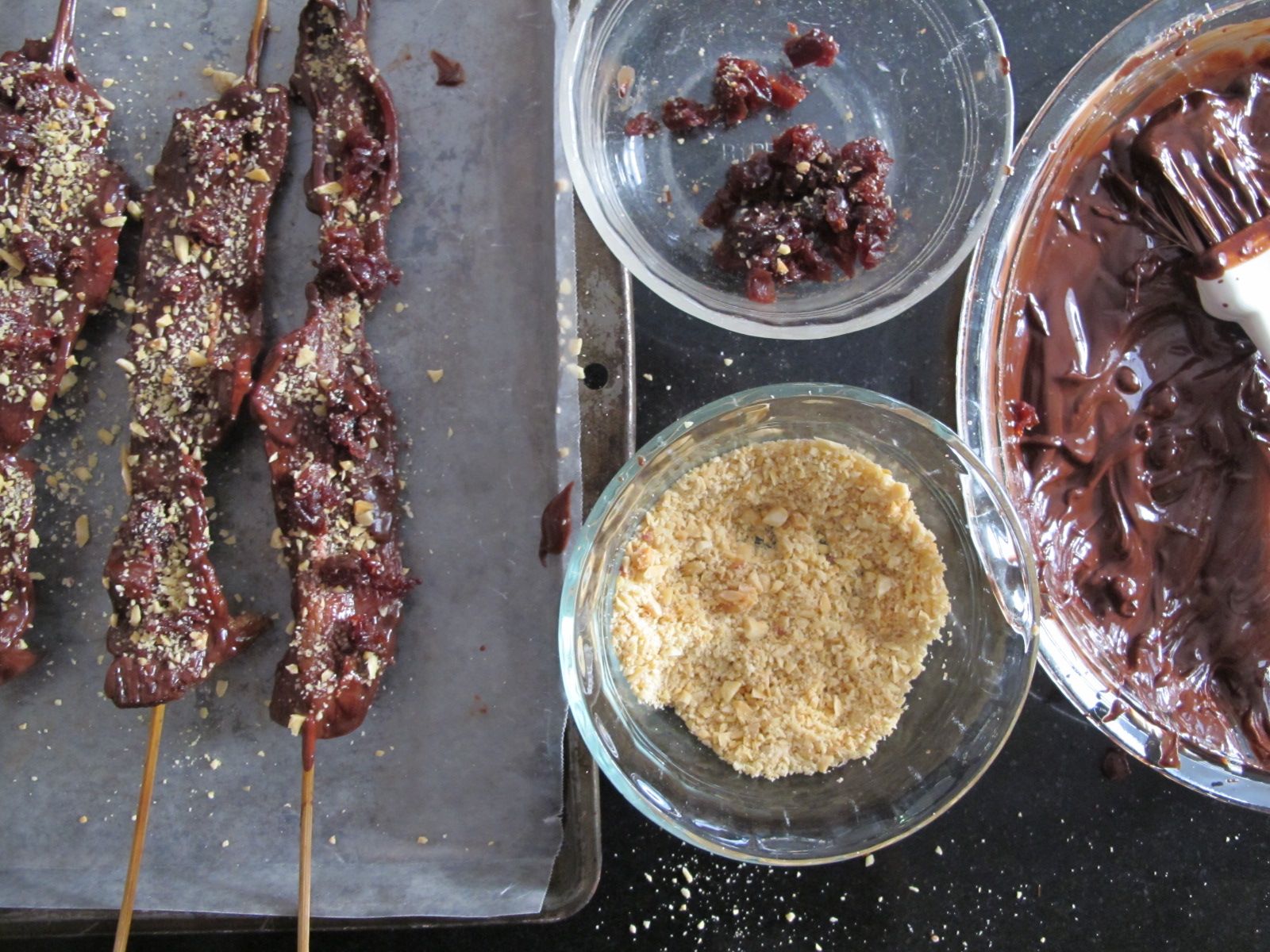 CHOCOLATE COVERED BACON ON A STICK WITH MARCONA ALMONDS AND DRIED CHERRIES